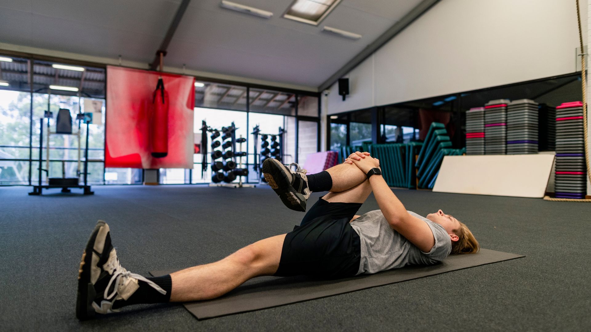 A man laying on a mat in a gym